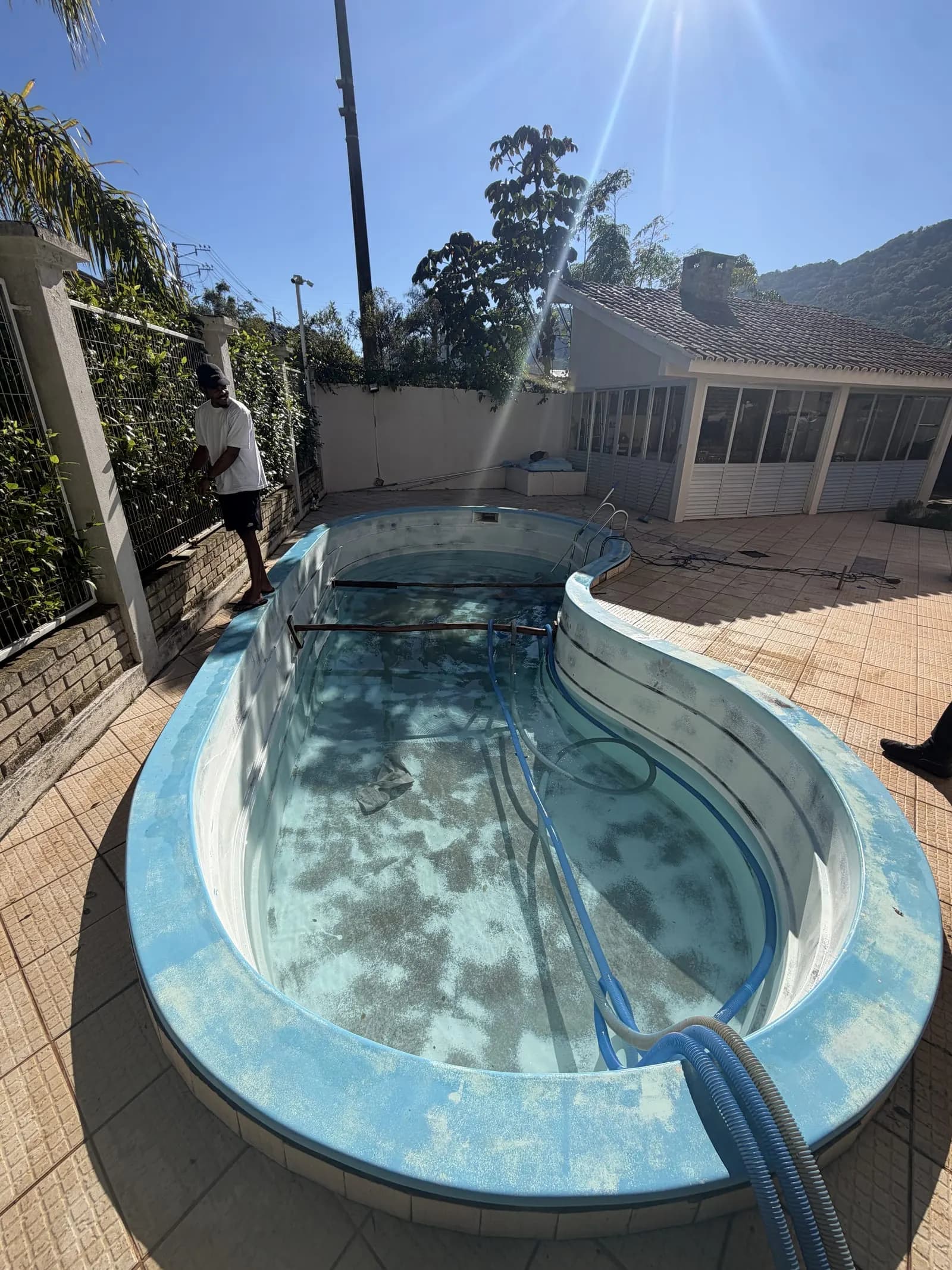Piscina de fibra antes da reforma, com acabamento desgastado, manchas e cor apagada.