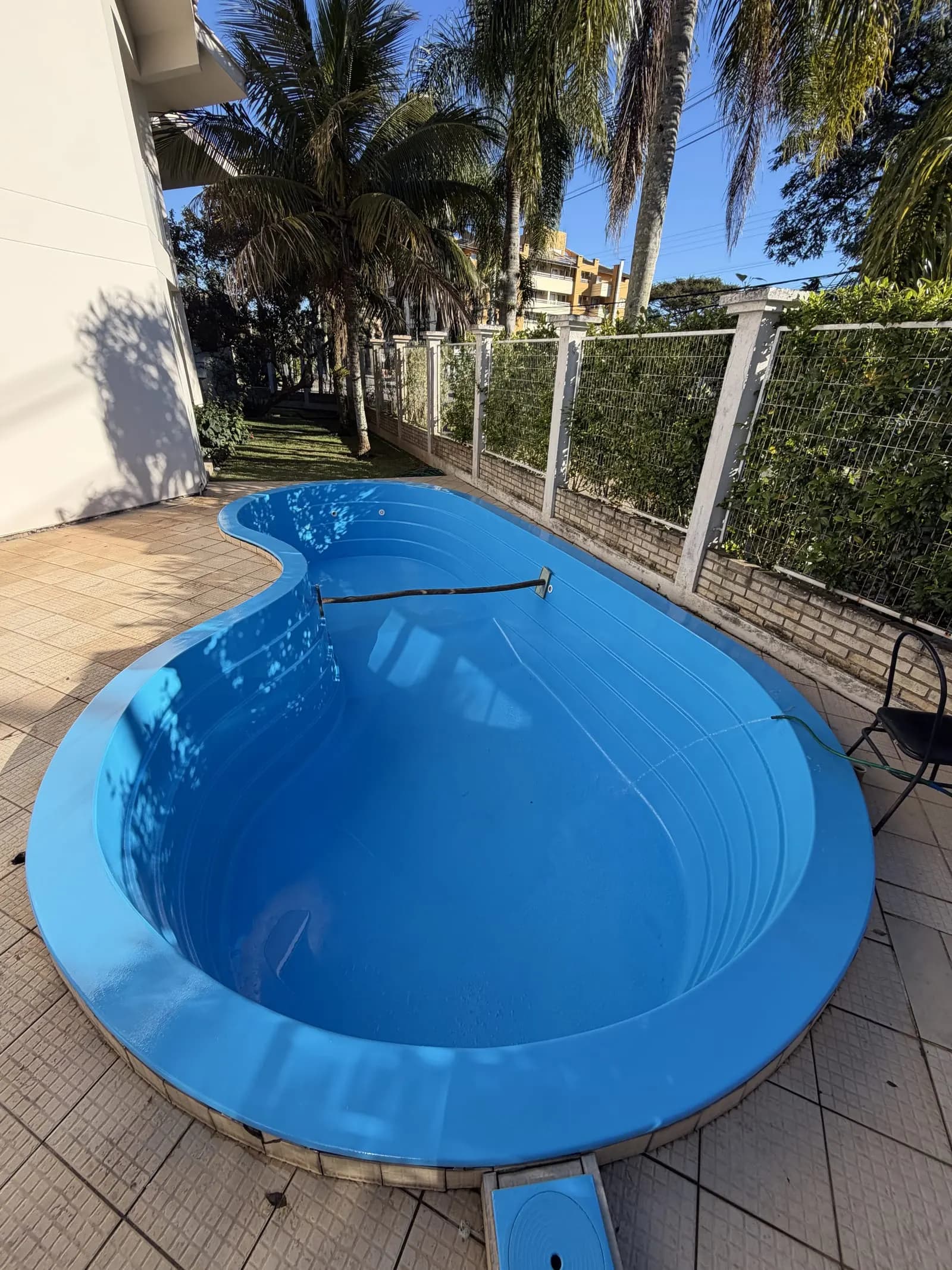 A mesma piscina de fibra depois da reforma, com acabamento azul vibrante e brilho renovado.