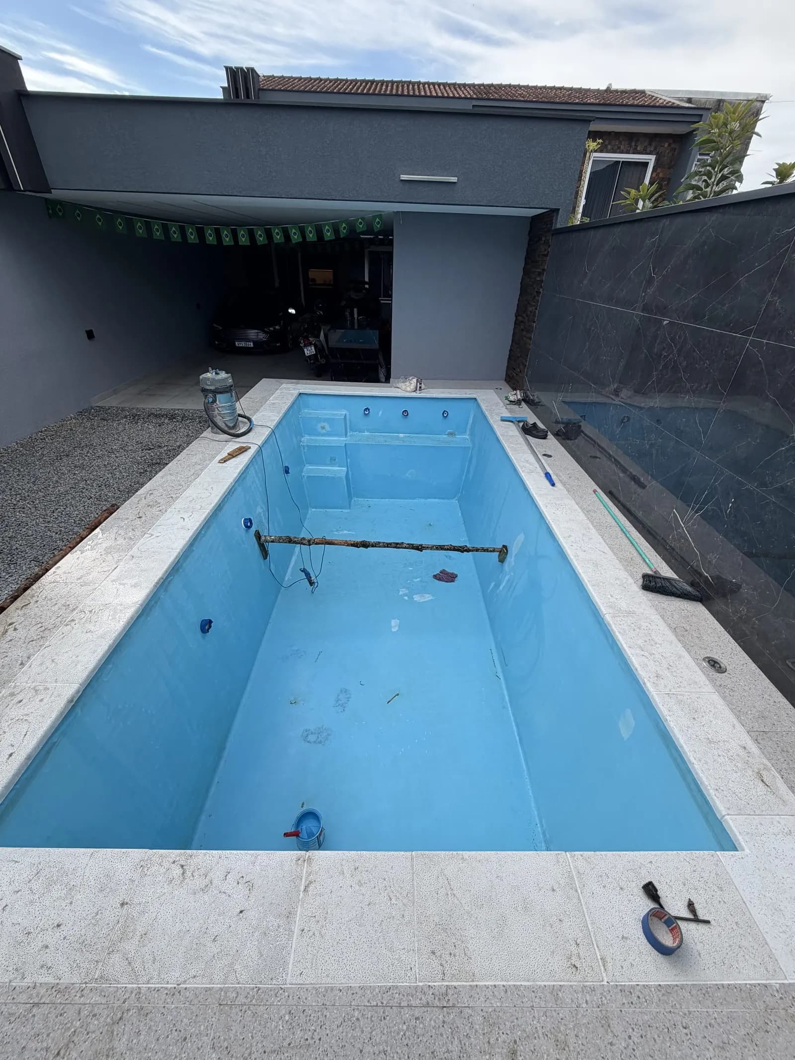 Piscina de fibra com a superfície preparada e base clara aplicada, antes da pintura final.