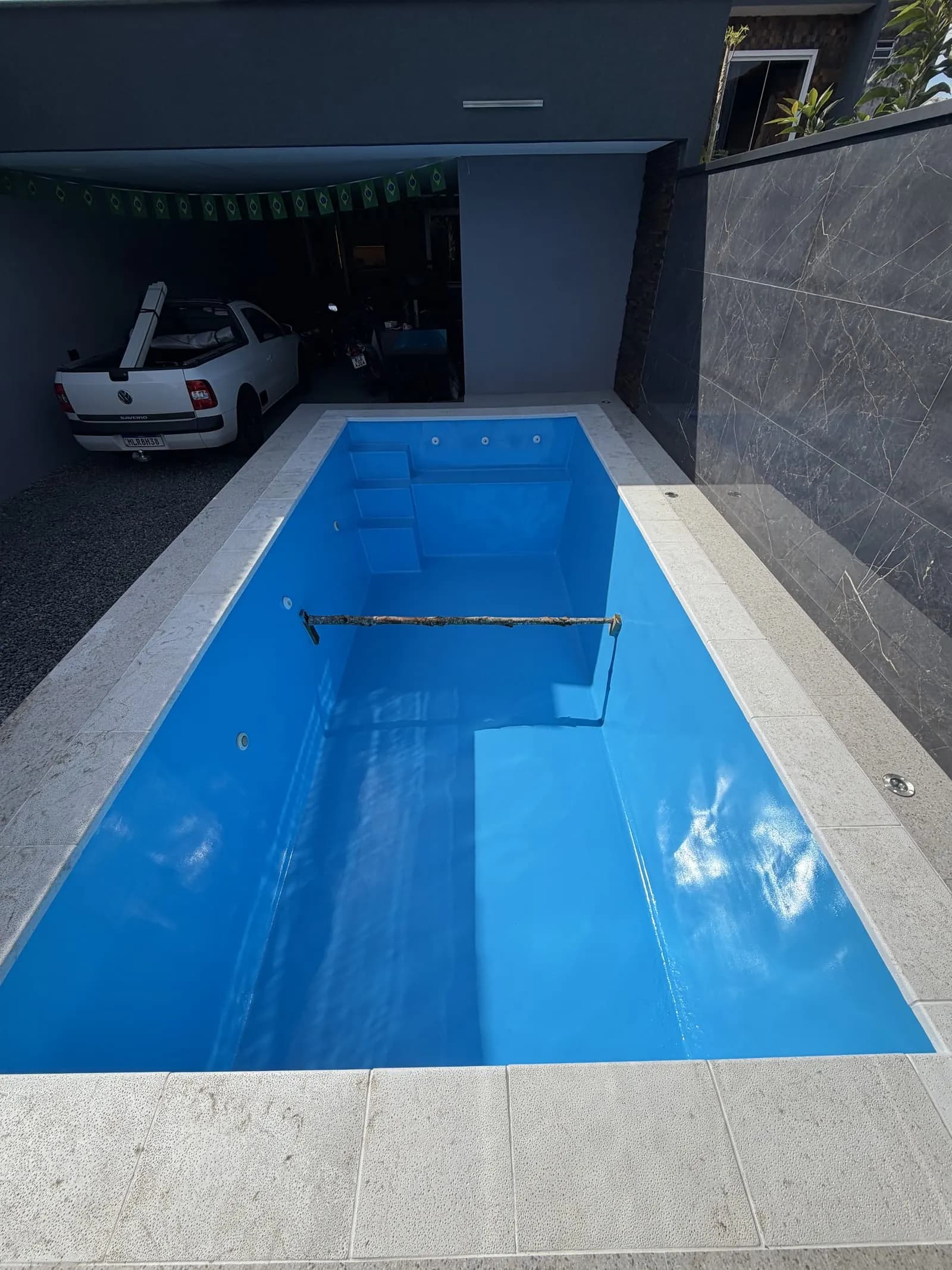 A mesma piscina de fibra com a pintura azul finalizada e acabamento brilhante.